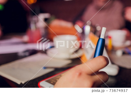 heat-not-burn tobacco product technology. Woman holding e-cigarette in his hand before smoking. heat-not-burn tobacco product technology. Woman holding e-cigarette in his hand before smoking. 73674937