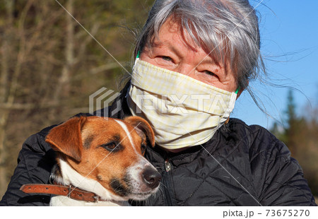 Senior elderly woman wearing white cotton home made virus mask her dog on hands. Life during coronavirus covid-19 outbreak illustration Senior elderly woman wearing white cotton home made virus mask her dog on hands. Life during coronavirus covid-19 outbreak illustration 73675270