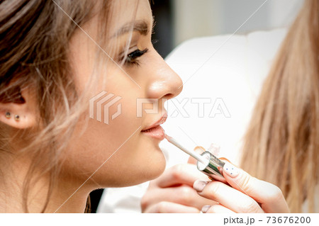 Artist's hand applying lipstick gloss Artist's hand applying lipstick gloss 73676200