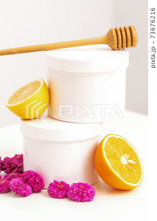 Jars with wooden honey stick, fresh lemon and flowers 73676216