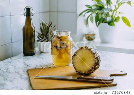 Fermented pineapple kombucha drink tepache. Cooking process of homemade probiotic superfood pineapple beverage. Drink jar and sliced pineapple on home kitchen Fermented pineapple kombucha drink tepache. Cooking process of homemade probiotic superfood pineapple beverage. Drink jar and sliced pineapple on home kitchen 73676348
