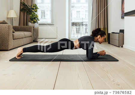 Side view of a slim woman in sportswear doing plank Side view of a slim woman in sportswear doing plank 73676582