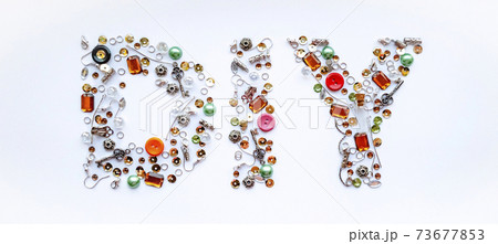 Diy lettering collected from handmade tools such as buttons, ear wires, locks, sequins, pendants on a white background. Craft and hobby concept. Banner format. Diy lettering collected from handmade tools such as buttons, ear wires, locks, sequins, pendants on a white background. Craft and hobby concept. Banner format. 73677853