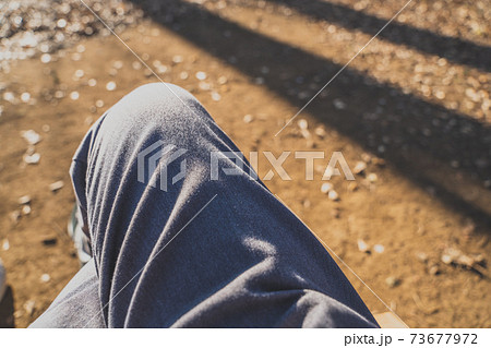 秋の公園のベンチで休憩する足を組んだ男性 73677972