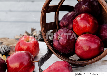 Harvest of red apples in a basket in autumn season, fresh organic fruits on wooden background 73677992