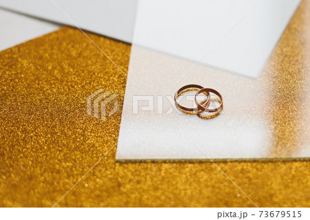 Two golden wedding rings on a golden background 73679515