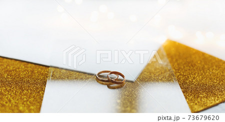 Two golden wedding rings on a golden background 73679620