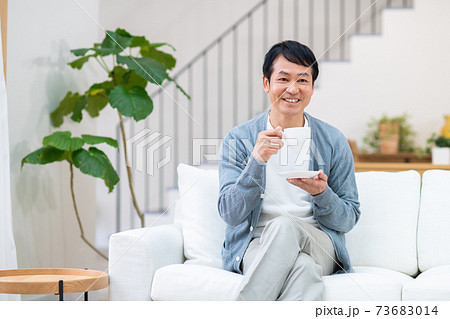 リビングでコーヒーを飲むミドルの男性 リビングでコーヒーを飲むミドルの男性 73683014