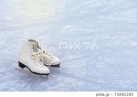 A pair of White Figure Skates are standing on an open ice rink. Winter sport 73692285
