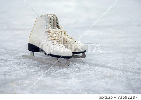 A pair of White Figure Skates are standing on an open ice rink. Winter sport 73692287