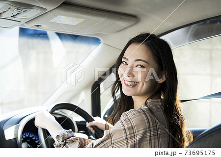 車を運転する若い女性 73695175