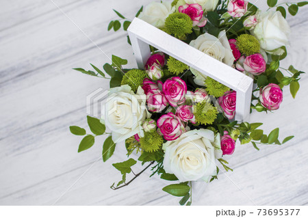 Wooden box with white and pink roses and chrysanthemums on white wooden board. Decoration of home. Flowers boxes. Wedding decoration Wooden box with white and pink roses and chrysanthemums on white wooden board. Decoration of home. Flowers boxes. Wedding decoration 73695377