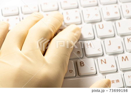 ゴム手袋をはめた手とキーボード の写真素材