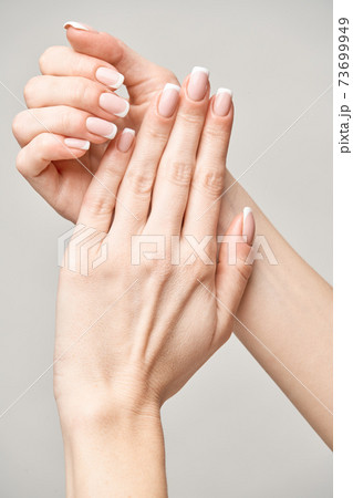 Beautiful Female Hands with French manicure over light grey background 73699949