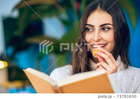 Young beautiful woman eating mandarin and smiling Young beautiful woman eating mandarin and smiling 73701630