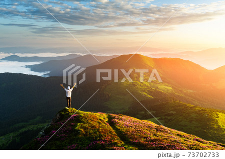 A tourist sits on the edge of a cliff A tourist sits on the edge of a cliff 73702733