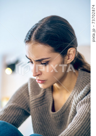 Dark-haired young woman looking stressed and unhappy 73702874