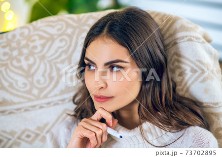 Woman looking thoughtful while making her wishlist 73702895