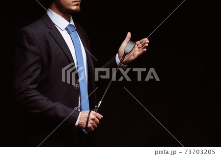 Male dominant businessman in a suit holding a leather whip Flogger for domination 73703205