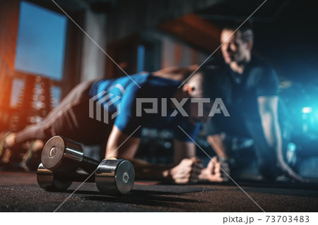 young man has workout with personal trainer in modern gym young man has workout with personal trainer in modern gym 73703483
