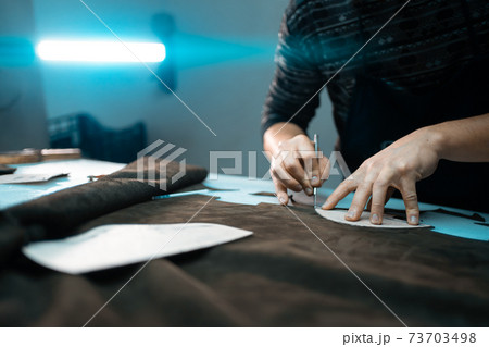 man shaping leather for shoe with knife on factory man shaping leather for shoe with knife on factory 73703498