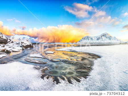 Incredible winter scenery on Skagsanden beach with illuminated clouds during sunrise. 73704312