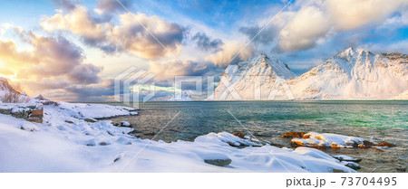 winter view of Vik beach during sunset with lots of snow  and snowy  mountain peaks near Leknes. 73704495