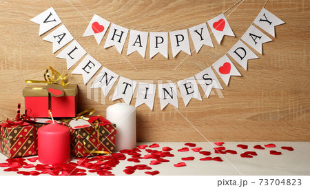 Happy Valentines day white flags garland, gifts with metallic ribbons, bows and labels with hearts, wax candles, red silk hearts on wood background. Love, Valentine's, romantic, rendezvous template Happy Valentines day white flags garland, gifts with metallic ribbons, bows and labels with hearts, wax candles, red silk hearts on wood background. Love, Valentine's, romantic, rendezvous template 73704823
