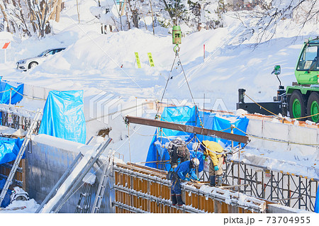 冬の水路工事現場のクレーン車による資材の吊り上げ 冬の水路工事現場のクレーン車による資材の吊り上げ 73704955