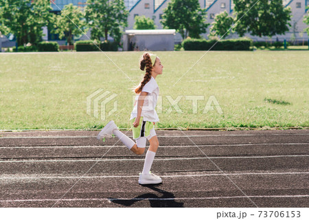 Girl jogging on a sunny summer evening, laying on treadmill, stadium, physical training, back to school. 73706153