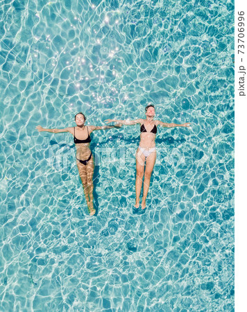 Couple of woman floating in transparent blue ocean. Aerial view Couple of woman floating in transparent blue ocean. Aerial view 73706996