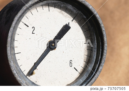 Old rusty round industrial pressure gauge with numbers on a white dial. Old rusty round industrial pressure gauge with numbers on a white dial. 73707505