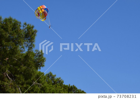 Parasailing in summer with colorful parachute, one persons in blue sky 73708231