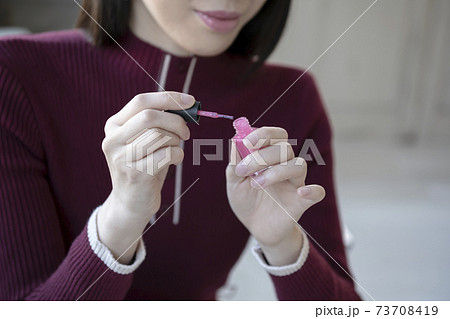 座ってマニュキュアを塗る女性 73708419