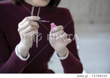 座ってマニュキュアを塗る女性 73708420
