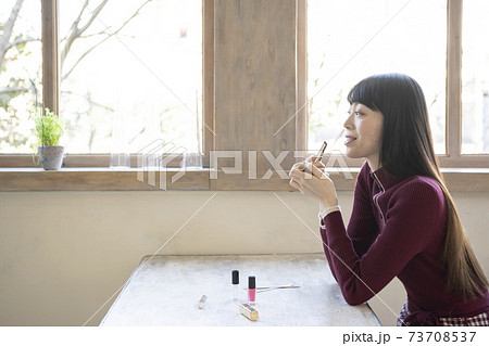 椅子に座って窓際で口紅を塗る女性 椅子に座って窓際で口紅を塗る女性 73708537