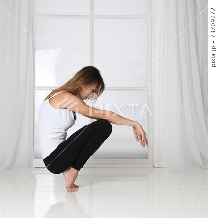 The woman squats, keeps her balance, fitness, fashion model posing The woman squats, keeps her balance, fitness, fashion model posing 73709272
