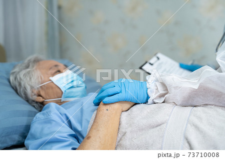 Asian doctor wearing PPE suit new normal to check patient protect safety infection Covid-19 Coronavirus outbreak at quarantine nursing hospital ward. 73710008
