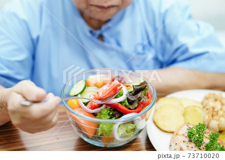 Asian senior or elderly old lady woman patient eating breakfast vegetable healthy food with hope and happy while sitting and hungry on bed in hospital. 73710020