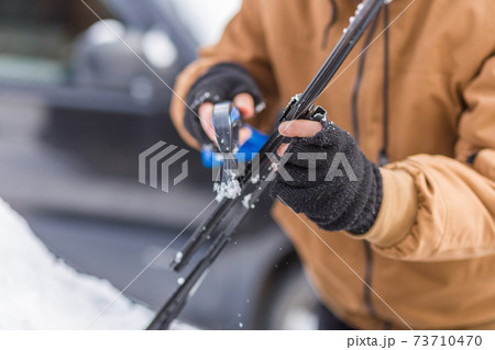 Man clear snow from car with cleaning tool Man clear snow from car with cleaning tool 73710470