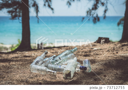 Close landfill old dirty transparent discarded empty glass alcohol drinks bottles trash on ground forest nature sea park. Alcoholism addiction problem bad habits, ecology issues environment pollution Close landfill old dirty transparent discarded empty glass alcohol drinks bottles trash on ground forest nature sea park. Alcoholism addiction problem bad habits, ecology issues environment pollution 73712755