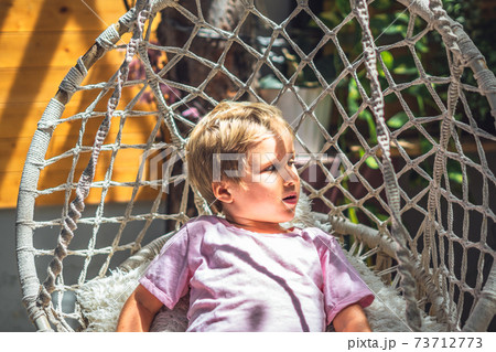 Cute smiling freckled blond boy emotion facial expressions gestures, intriguing funny mischievous in pink, look sun beams sit Hammock Chair Hanging. Happy childhood mood, children behaviour concept 73712773