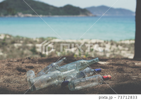 Close landfill old dirty transparent discarded empty glass alcohol drinks bottles trash on ground forest nature sea park. Alcoholism addiction problem bad habits, ecology issues environment pollution Close landfill old dirty transparent discarded empty glass alcohol drinks bottles trash on ground forest nature sea park. Alcoholism addiction problem bad habits, ecology issues environment pollution 73712833