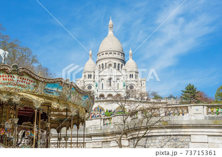 Tourists stroll in Montmartre near Basilica Sacre Coeur (designed by Paul Abadie, 1914) - Roman Catholic Church and minor basilica, dedicated to Sacred Heart of Jesus 73715361