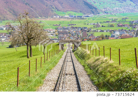 Trees and railway on the foot of Mt. Stanserhorn in Switzerland in the beginning of May. Mt. Stanserhorn is a mountain located in the Swiss canton of Nidwalden, near the town of Stans. 73715624