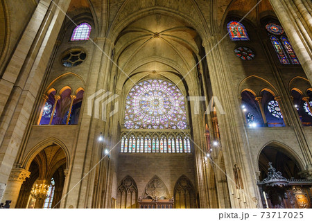 Dark interior of Cathedral of Notre Dame de Paris. Stained-glass window and candles with tall columns. Dark interior of Cathedral of Notre Dame de Paris. Stained-glass window and candles with tall columns. 73717025