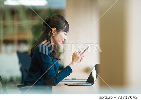 コワーキングスペースでスマホを見る女性 73717045