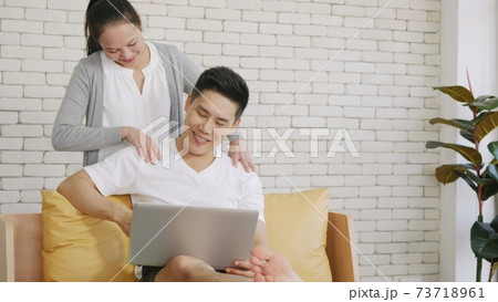 family couple husband and wife laughing sitting on sofa using laptop computer working from home 73718961
