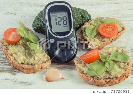 Glucose meter for checking sugar level and sandwiches with paste of avocado 73720951