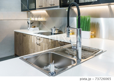 Stainless kitchen sink and Tap water in the kitchen. The interior of the kitchen room of the apartment. Built-In Appliances. Kitchen Appliance. Domestic Appliances Stainless kitchen sink and Tap water in the kitchen. The interior of the kitchen room of the apartment. Built-In Appliances. Kitchen Appliance. Domestic Appliances 73726065